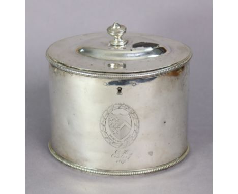 A George III silver oval straight-sided tea caddy with vase finial to the slightly domed hinged lid, beaded rims, engraved ar