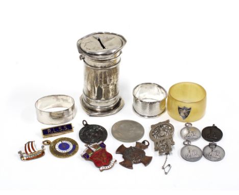 Two silver napkin rings, a horn napkin ring with silver shield, a silver money bank (a/f) three silver fob medallions, enamel