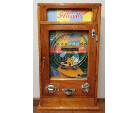 A mid century Oliver Whales Allwin '9 results' arcade/amusement machine, the penny slot with manual payout, with pictorial ba