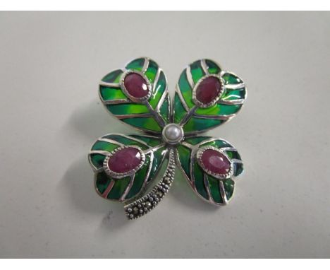 A silver and enamelled brooch fashioned as a four leaf clover, set with rubies, a pearl and marcasites 