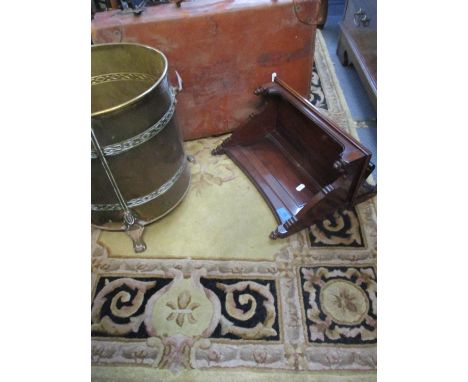 An Indian scatter rug, a brown vintage leather suitcase, a brass coal bucket on three feet, and a mahogany wall mounted book 