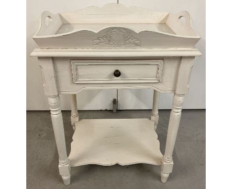 A wooden occasional table with fixed tray style top, central drawer and under shelf.  Painted white, with turned legs and met