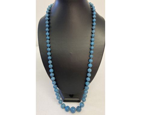 A long graduating turquoise bead necklace with vintage white metal clasp.  Necklace is knotted between each bead.  Total leng