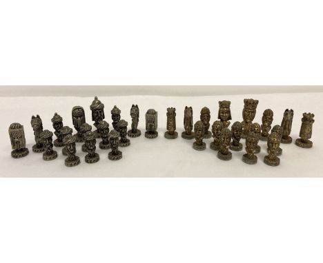 A set of cast metal Medieval style Chess playing pieces in a wooden tray.  Silver and gold coloured playing pieces with green