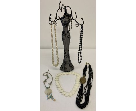 A jewellery stand in the shape of a evening dress together with a small collection of necklaces.  To include 1980's white pla