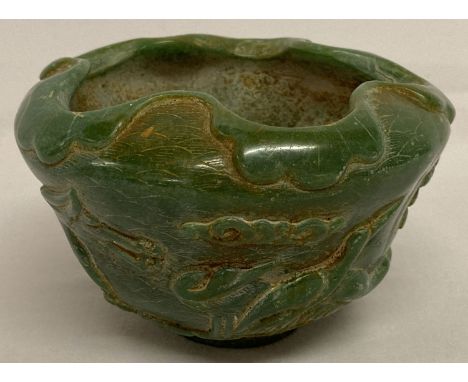 A carved green jade Chinese bowl with cherry blossom and bird decoration to outer bowl.  Scalloped shaped rim.  Approx. 8cm t