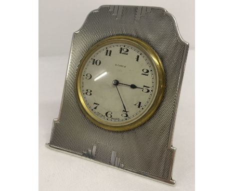 A small Art Deco silver framed bedside/table 8 day clock with engine turned decoration.  Rear stand detached, clock not worki