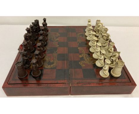 A Chinese chess set in folding wooden case with gilt dragon &amp; pheasant decorative detail.  Brass handles and catch. Case 