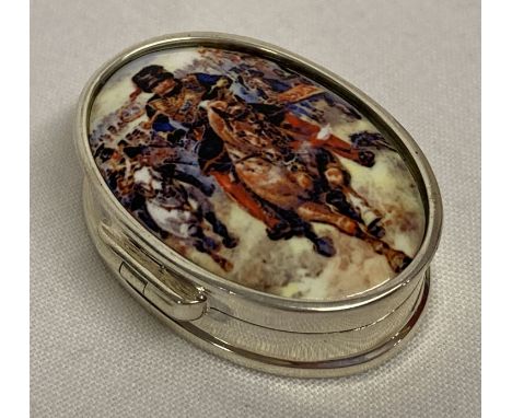 A small oval shaped pill box with ceramic plaque set to lid depicting charging cavalrymen.  Marked "Sterling" to interior.  A