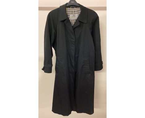 A ladies black rain mac by Aquascutum. Chequered lining with both exterior and interior pockets.  Front button fastening with