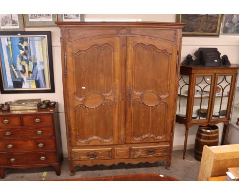 A large oak French armoire with interior shelf and hanging compartment, two long drawers below, raised on squat cabriole supp