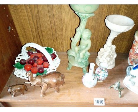 A shelf of ceramic items including a brass Asian baby