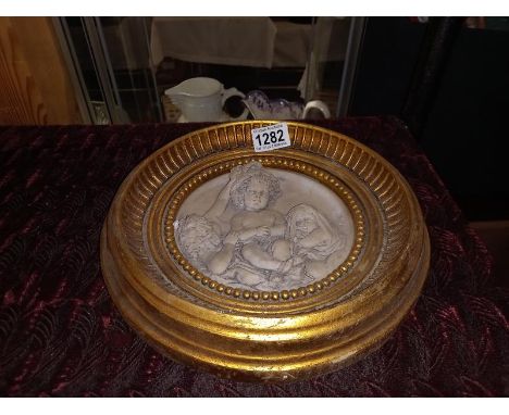 A framed cherub plaque.