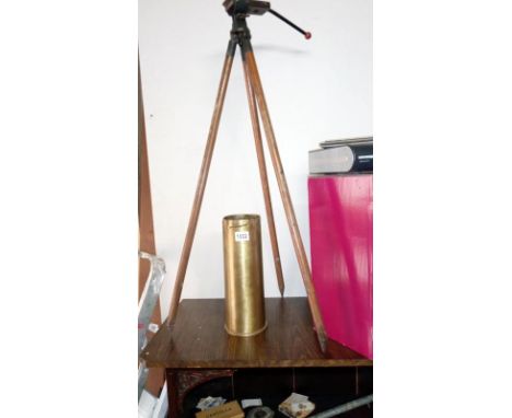 A vintage camera tripod on spike legs and a brass spent shell