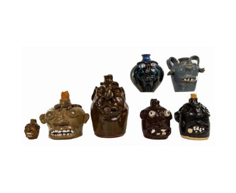 Face Jug Pottery Assortment  (7) jugs including in dark brown smoking a cigar, signed 'Brown's Pottery, Robert Brown' on unde