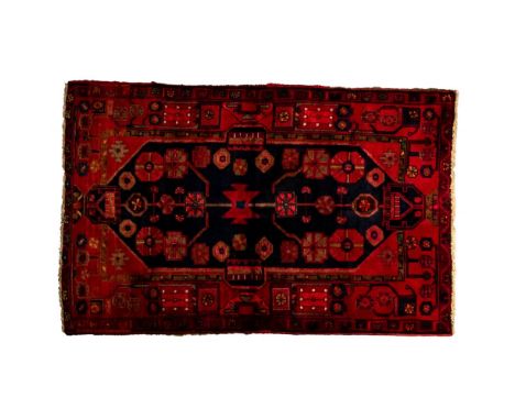 Wool Area Rug  Woven rug having a red field with a geometric botanical motif in shades of blue, green and ivory; short fringe