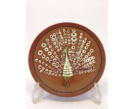 A Poole Pottery Atlantis period small plate, decorated with a stylised Peacock type bird with outspread wings, decorated in w