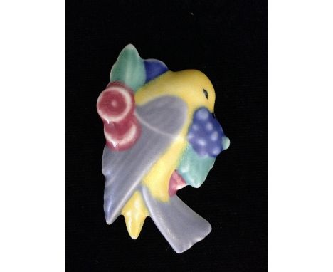 A Poole Pottery brooch, modelled as a bird holding grapes in its mouth, decorated in tones of yellow, blue, green, grey and r