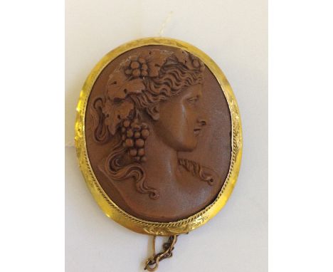 A Victorian lava Cameo brooch modelled as an Art Nouveau style portrait of a female with flowing grape and vine hair in 9 car