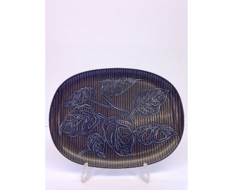 A Poole Pottery Studio dish, decorated by Ann Read in a freehand Philodendron pattern, drawn as seven leaves on brown and bla