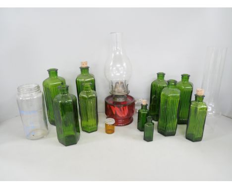 An oil lamp with cranberry glass reservoir, together with a collection of ten green glass and one other medical bottles **PLE