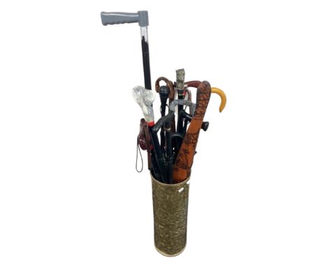 A cylindrical brass stick pot containing walking sticks, tourist boomerang, umbrella etc.