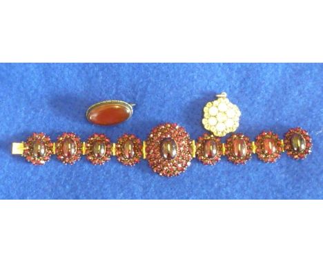 A ladies white metal bangle set with oval cabouchon style garnets together with a small oval Brooch set with a red hardstone 