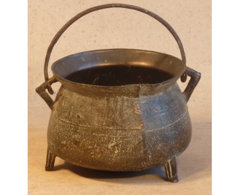 An 18th/19th Century bronze Cauldron with iron loop swing handle, two angular handles and tripod base in usual form, 33cm wid