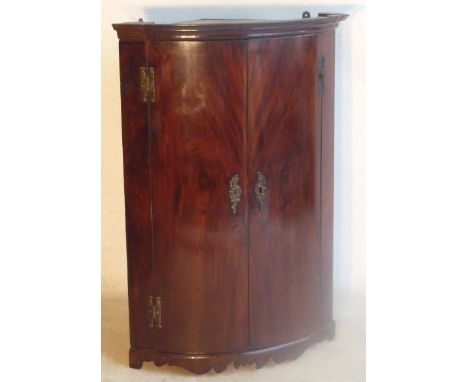 A late 18th/early 19th Century George III period bow fronted mahogany hanging Corner Cupboard, the doors with 'H' form hinges