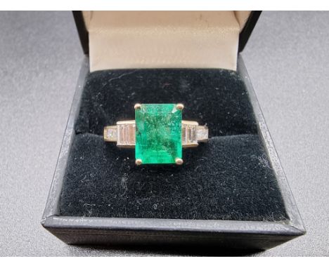 A yellow metal ring, set rectangular emerald with baguette and carre cut diamonds to shoulders, stamped 14 k, size O 1/2. 