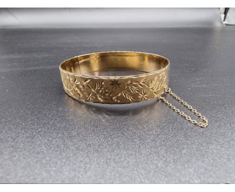 A 9ct gold hinged oval bangle, having textured and chased floral decoration, by B Ltd, Birmingham 1991, 60mm, 23.5g. 