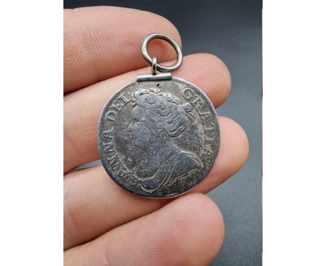 Coins: a Queen Anne silver shilling, with attached suspension ring. 