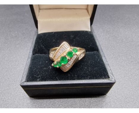 An emerald and diamond crossover ring, set five graduated emeralds to centre surrounded by diamonds, stamped 14kt, size P. 