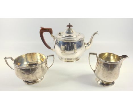 GEORGE V SILVER THREE PIECE TEASET COMPRISING A CIRCULAR BALUSTER TEAPOT, WITH DART AND TOOTH STYLE DECORATED RIM AND BRACKET