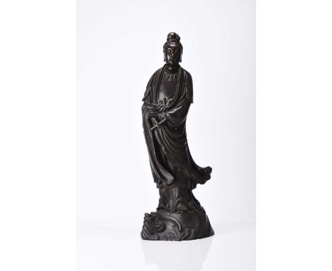 A large Chinese silver-inlaid bronze figure of Guanyin, Qing DynastyModelled standing on top of a dragon, she wears flowing r