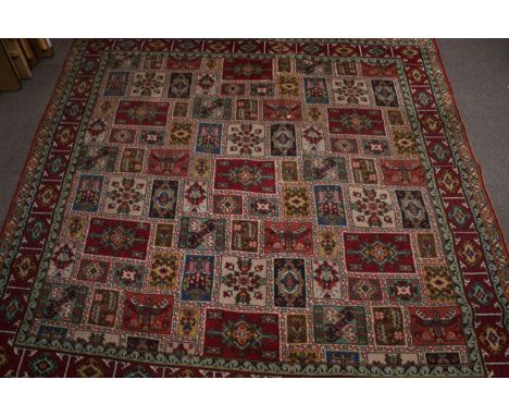 A large square patterned wool carpet rug. With red geometric boarder, 270cm x 266cm