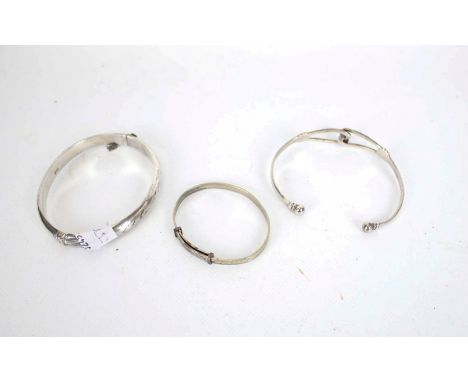 Three silver bangles including a torque bangle