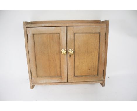 A small limed pine wall unit. With a single shelf behind double doors. H55cm x W62cm x D18cm