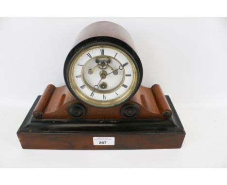 An early 20th century ebonised and mahogany mantel clock. On a rectangular stepped base with French movement, white enamel di