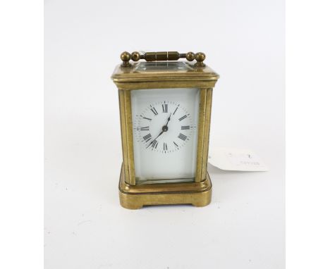 A miniature brass carriage clock. Unmarked, white enamel dial with Roman numerals, bevelled glass, no key, H7cm