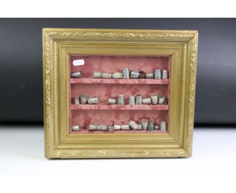 A framed and glazed collection of metal thimbles to include fully hallmarked sterling silver examples. 