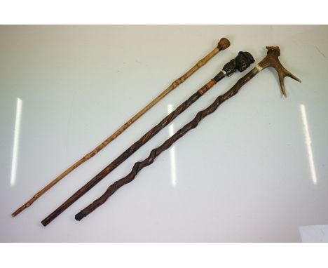 Three Folk Art wooden walking sticks to include a Black Forest style example with carved figural pommel, a further figural ex