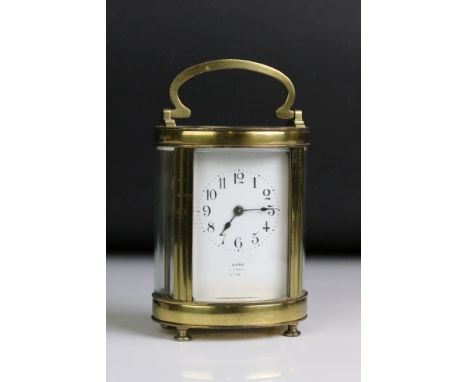 A French made antique brass cased carriage clock with rounded bevelled glass panels and white enamel dial. 