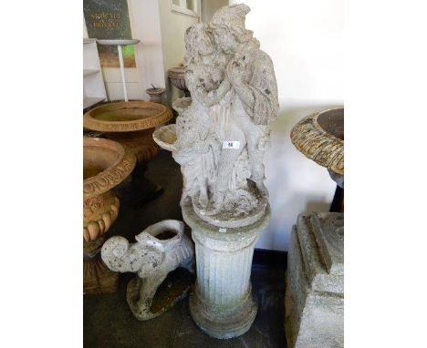 A concrete garden statue in the form of a male and female figure, raised on a fluted column and one other larger column