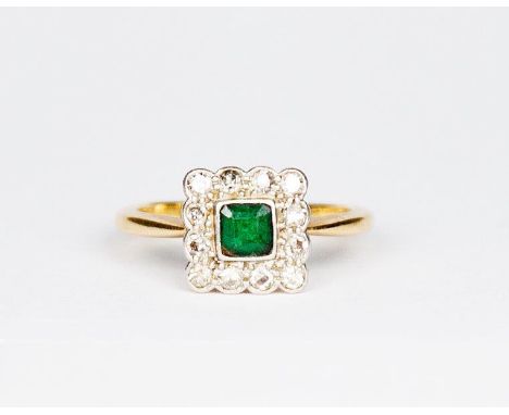 A lady's ring set centre square emerald surrounded by diamonds, on an 18ct. gold shank
