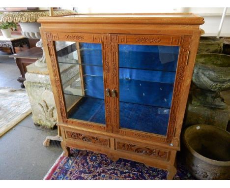 A Chinese display cabinet with carved decoration of prunus flowers, fitted two glass doors and sides, the base fitted two dra