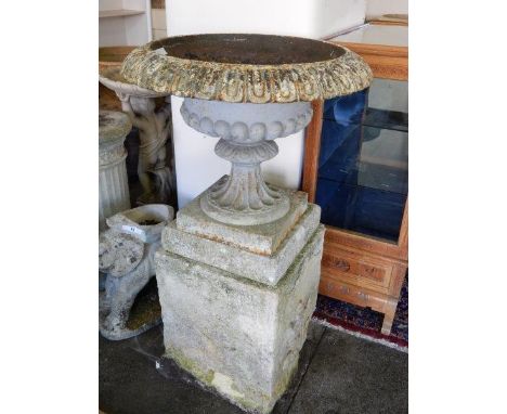 A pair of cast iron garden urns with fluted decoration, on square bases, complete with concrete plinths