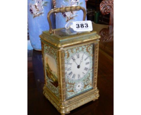 A carriage clock with turquoise and gilt face, circular white enamel dial and alarm dial, in an engraved brass case with inse