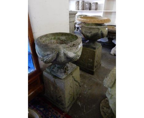 A pair of concrete garden urns with swag decoration, complete with square bases