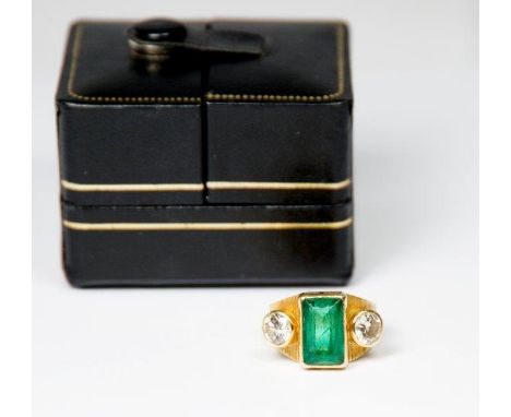 A lady's ring set rectangular emerald flanked to each side by diamonds, on an 18ct. gold shank